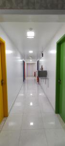 un pasillo vacío con puertas verdes y suelo de baldosa blanca en Guest House Renascer K&W, en Cabo Frío