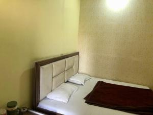 a bedroom with a bed with a headboard and two pillows at Hotel Abhishek in Jhānsi