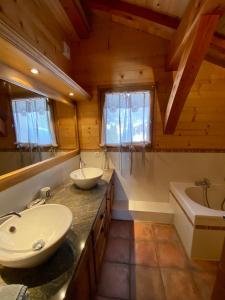 uma casa de banho com 2 lavatórios, uma banheira e um lavatório. em Chalet Pétérets em Samoëns