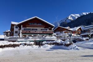 a building with snow on the ground in front of it at Hotel Jagdhof in Riezlern