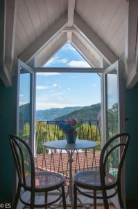 einen Tisch und Stühle vor einem großen Fenster in der Unterkunft Casa della Musica in Verbania