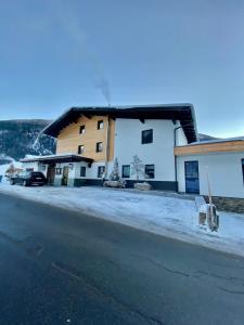 a building with snow on the ground next to a street at Pension Bucher in Schnann