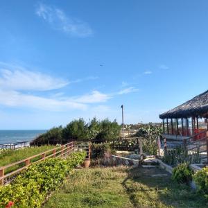 um jardim com um gazebo e o oceano em HOTEL DAS FALESIAS em Beberibe