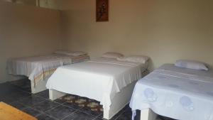 a room with two beds with white sheets at Montañita Garden Hostal in Montañita