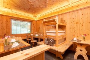 Cette chambre en bois comprend une table, des chaises et une étagère. dans l'établissement Alpenhotel La Montanara, à Rocca Pietore