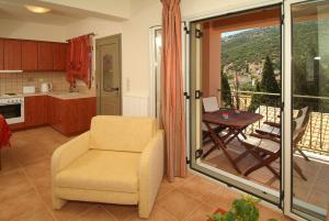 a kitchen with a chair and a balcony with a table at GARDEN VILLAS in Ayia Evfimia