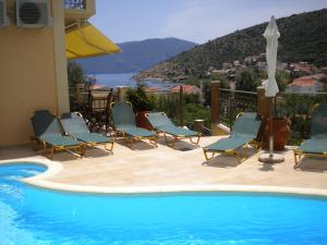 - un groupe de chaises assises à côté de la piscine dans l'établissement GARDEN VILLAS, à Agia Effimia