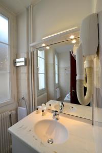 a white sink sitting under a mirror in a bathroom at Hôtel d’Angleterre Grenoble Hyper-Centre in Grenoble