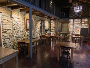 a restaurant with wooden tables and chairs and a stone wall at Hotel Cruells in Planoles