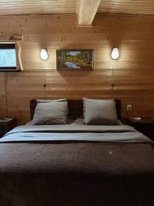 a bed in a wooden cabin with two lights above it at Taulu in Dombay