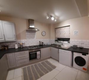 uma cozinha com um fogão e uma máquina de lavar louça em Cosy 3 bedroom residential house, private garden, 30 minutes from Alton Towers, 5 minute walk to Trentham Gardens. em Stoke-on-Trent