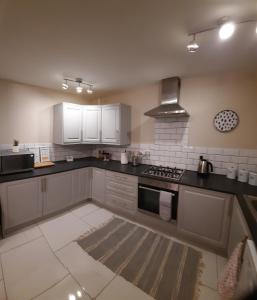 a kitchen with white cabinets and a stove top oven at Cosy 3 bedroom residential house, private garden, 30 minutes from Alton Towers, 5 minute walk to Trentham Gardens. in Stoke on Trent