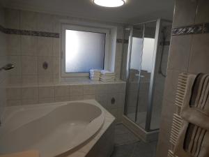 een badkamer met een bad en een douche en een raam bij Landhaus Gollner in Uderns