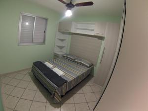a bed in a room with a ceiling fan at Apartamento charmoso a 50m da praia in Caraguatatuba