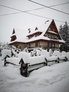 eine Gruppe von vor einem Gebäude mit Schnee bedeckten Bänken in der Unterkunft Pokoje gościnne Zosia in Kościelisko