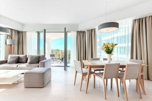 een woonkamer met een tafel en stoelen en een bank bij Dreams apartments Dune B in Mielno