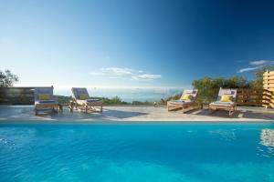 a group of lounge chairs and a swimming pool at Villa Alma - Melisou Villas in Kalamitsi