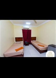 Makkah Hotel في Qinā: غرفة بسريرين وستارة حمراء