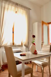 a dining room table with chairs and a vase with a rose at Appartamento Il Giglio in Viterbo