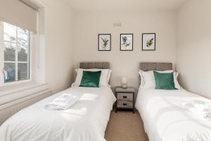 dos camas sentadas una al lado de la otra en un dormitorio en Cosy, Exclusive, Sheffield House near Peak District by Ark SA, en Sheffield