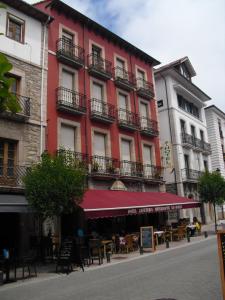 a red building with tables and chairs in front of it at Hotel Los Robles in Cangas de Onís