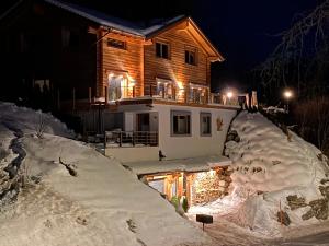 une maison recouverte de neige la nuit avec des lumières dans l'établissement Chalet Aigle, à Crans-Montana