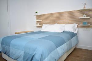 Schlafzimmer mit einem blauen Bett und einem Kopfteil aus Holz in der Unterkunft SUNNY BEACH APARTMENT IN CALACEITE in Torrox Costa
