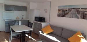 ein Wohnzimmer mit einem Sofa und einem Tisch sowie eine Küche in der Unterkunft Superbe appartement piscine centre port - belle vue - parking in Cap d'Agde