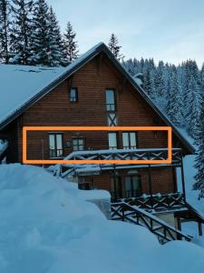 una cabaña de madera con nieve delante en Pino apartman Jahorina, en Jahorina