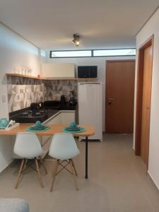 a kitchen with a table and two chairs and a refrigerator at Flat Macaraípe - Maraca Beach I in Porto De Galinhas