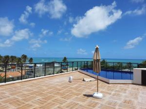a patio with an umbrella and the ocean at Flat Macaraípe - Maraca Beach I in Porto De Galinhas