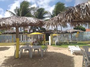 uma mesa e cadeiras debaixo de um guarda-sol de palha na praia em Girassol Pousada em Extremóz
