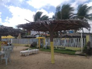 a palm tree with a straw umbrella on the beach at Girassol Pousada in Extremóz