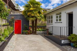 a palm tree in front of a house with a red door at Seaview Apartment in Picton