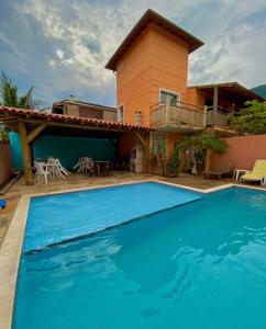 a villa with a swimming pool in front of a house at CHALÉS e SUITES PORTO SEGURO in Maresias