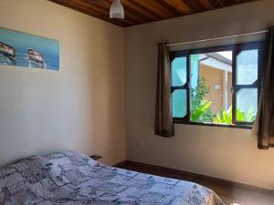 ein Schlafzimmer mit einem Bett und einem großen Fenster in der Unterkunft Le Marchand de Sable- Suites e apartamento in Búzios + 29 Fotos