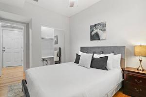 ein weißes Schlafzimmer mit einem großen weißen Bett und einer Lampe in der Unterkunft 1BR Deluxe Apartment near Shops & Cafés - Ashland 1F in Chicago