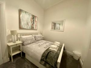 a small bedroom with a bed and a night stand at Cosy Cottage in Stirling