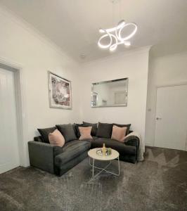 a living room with a black couch and a table at Cosy Cottage in Stirling