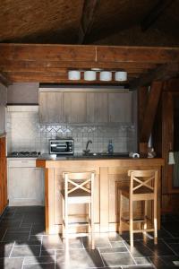 a kitchen with a counter and two stools in it at Le Chalet Pré de la Fontaine in Paliseul