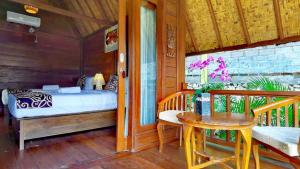 a bedroom with a bed and a table on a porch at Cersen Resort Lombok in Kuta Lombok