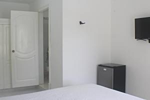 1 dormitorio con 1 cama y TV en la pared en Sweet Home Punta Cana Guest House - VILLA Q15A, en Punta Cana