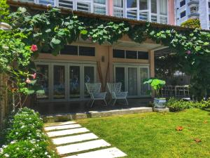 une maison avec deux chaises et un jardin dans l'établissement Smell rose beach garden, à Batu Ferringhi
