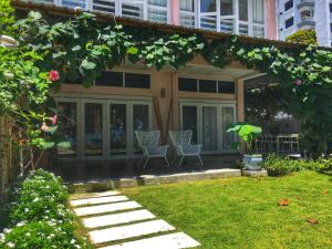 a house with two chairs and a garden at Smell rose beach garden in Batu Ferringhi