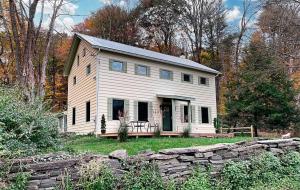 a small white house with a stone wall at Catskill home with King bed, indoor hot tub and BBQ near Woodstock and skiing in Saugerties