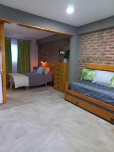 a bedroom with two beds and a brick wall at LA CASA DE COCO ALOJAMIENTO TURÍSTICO in Dina Huapi