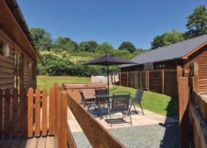 een patio met een tafel en stoelen en een parasol bij Heartsease Lodges in Llanbister