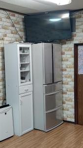 um frigorífico branco num quarto com uma parede de tijolos em HILDA INN em Kashiwa