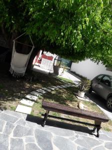 Alojamiento Moni في مار ديل بلاتا: كرسي خشبي جالس على رصيف تحت شجرة
