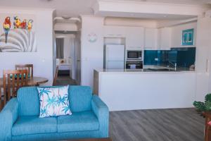 a living room with a blue couch and a kitchen at Surfers Horizons in Gold Coast